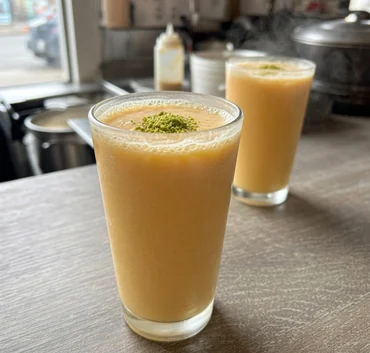 Glass of mango lassi topped with crushed pistachio